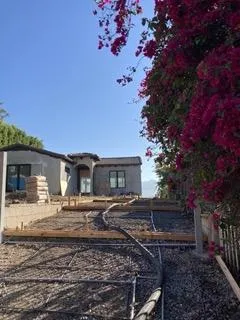 Image of a formed driveway yet to have concrete poured into it with the concrete pump hose running up the driveway and out of view.