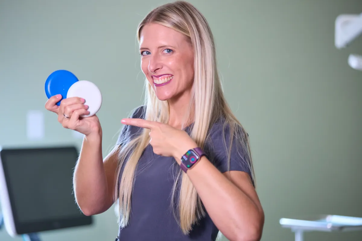 Dr. Cynthia Blalock of Cardinal Dental in St. Peters, MO, holding Invisalign clear aligner cases and smiling