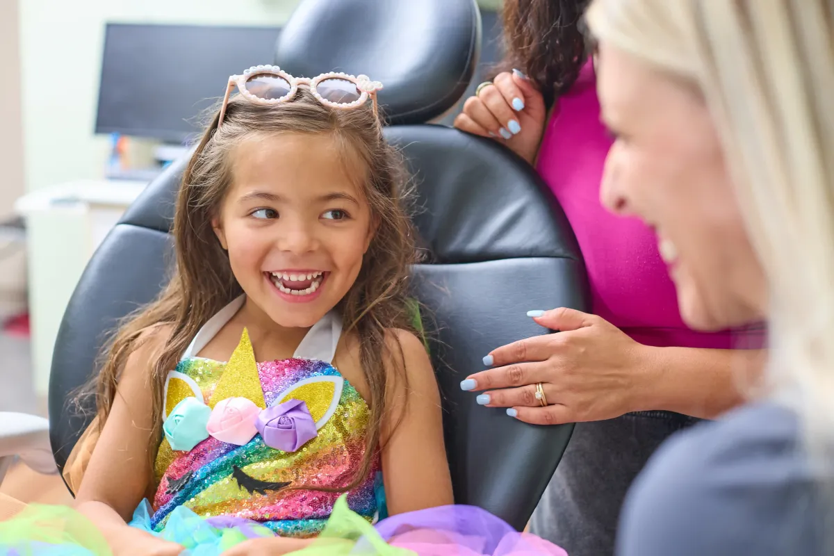 A young patient laughing with the Cardinal Dental team during a comfortable and fun pediatric dental visit