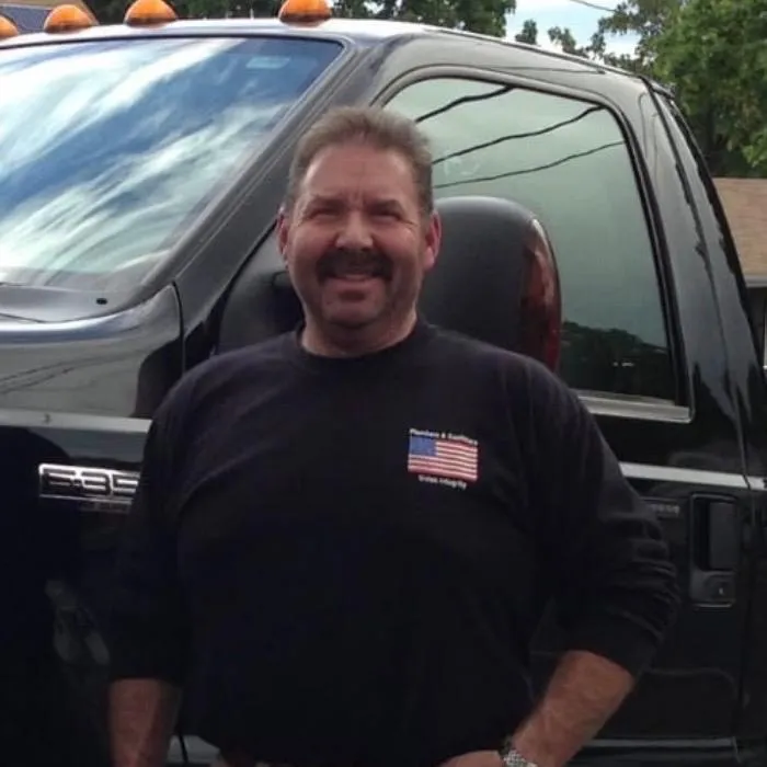 Owner of Pescatore Plumbing and Heating standing beside company service truck