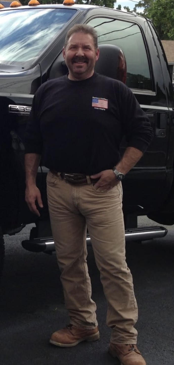 Pescatore Plumbing technician standing in front of branded service van in Boston
