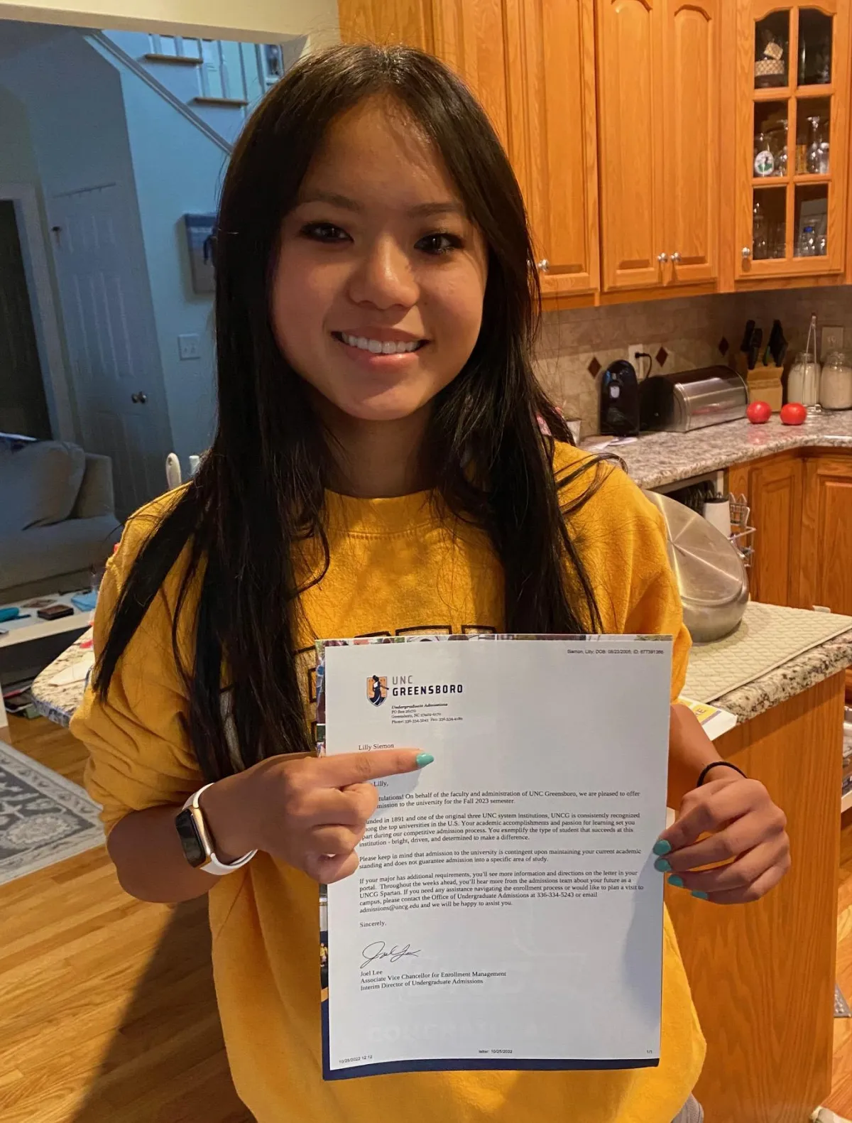 Smiling student pointing to college acceptance letter.