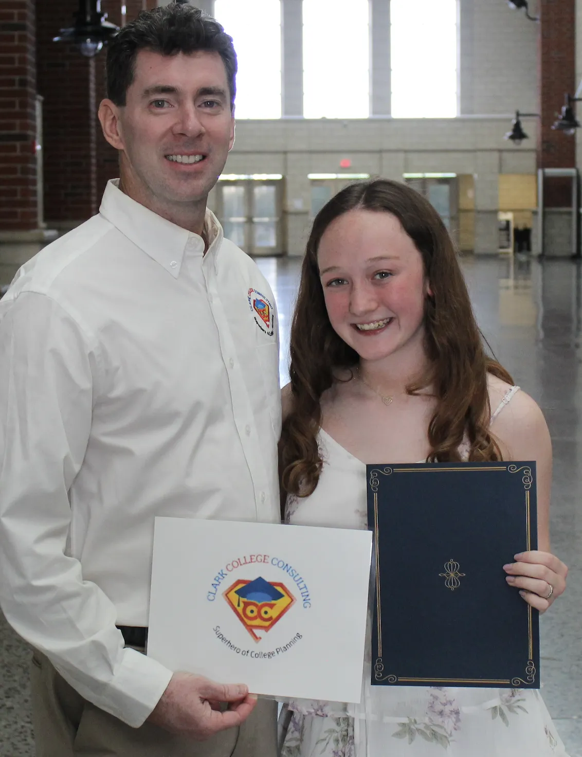 Ryan Clark and high school student smiling and holding a scholarship.