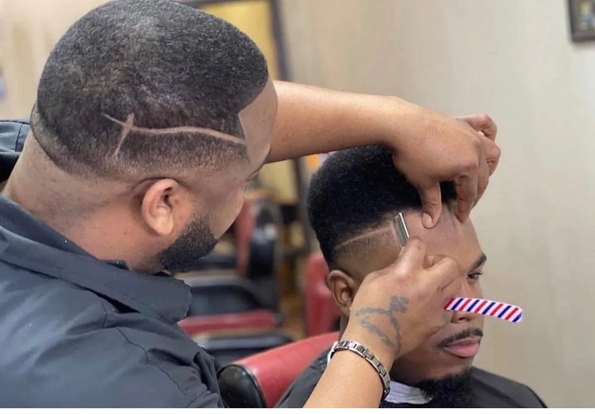 Master barber focused on precision detailing in a high-contrast black and white salon setting