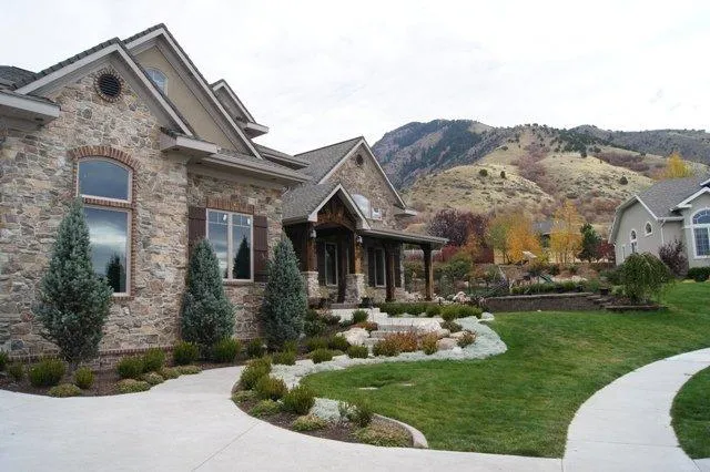 Image shows a new entry of a home with new trees, new shrubs, a mowed green lawn and flowers. landscape enhancement in cache valley utah