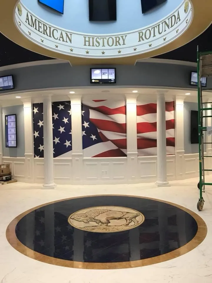 Interior of the American History Rotunda in the Buffalo Pacific prototype, featuring an enlarged $50 US Gold Coin emblem on the floor, a large American flag mural, and classical columns, representing the company’s dedication to honoring national history.