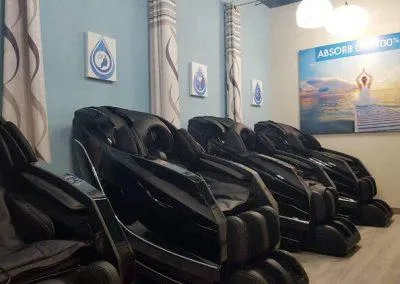 Therapy lounge at Prime IV Infusion Center in Dayton, featuring comfortable black recliner chairs, soothing blue accents, and serene wall art, all designed to provide a relaxing environment by Drake Architecture.