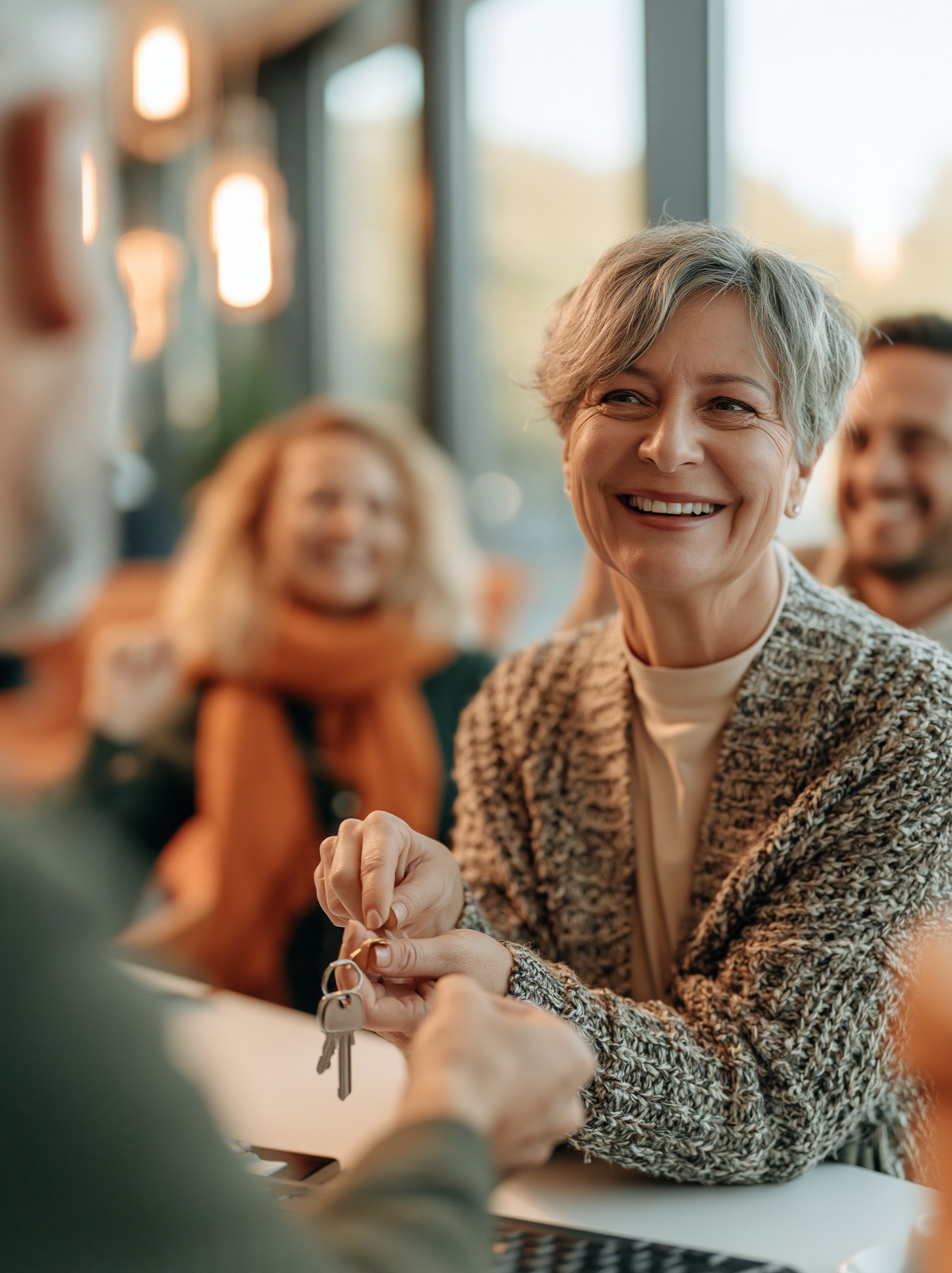 A title company closing officer handing house keys to a happy first-time-buyer couple at a closing table