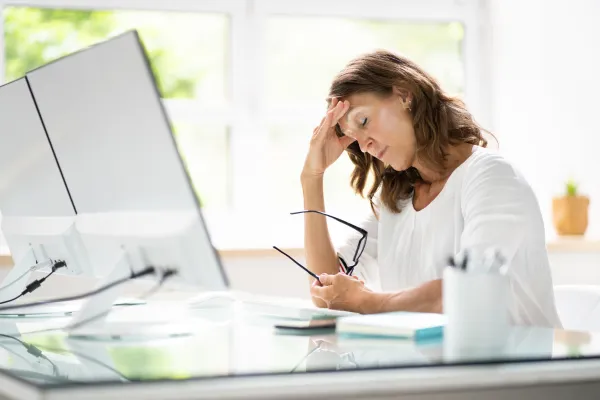 Stressed homeowner reviewing bills at kitchen table while considering selling their home in Owasso Oklahoma