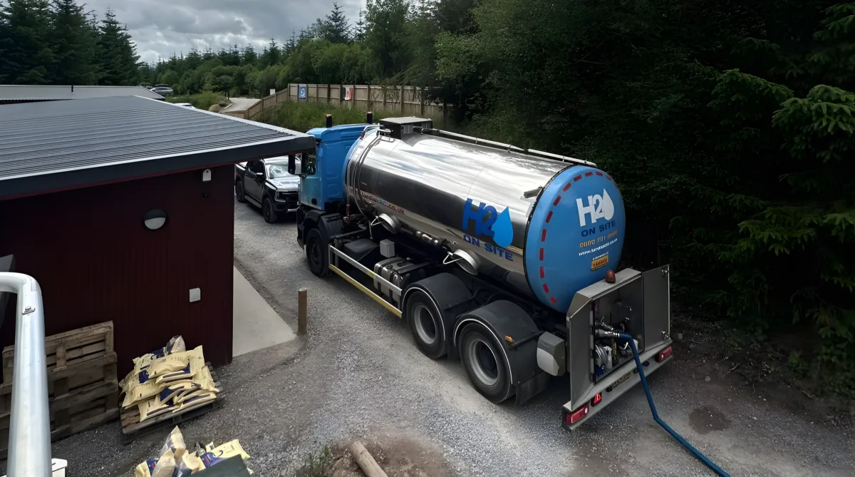 Water delivery truck labeled “H2O On Site” parked beside a building.