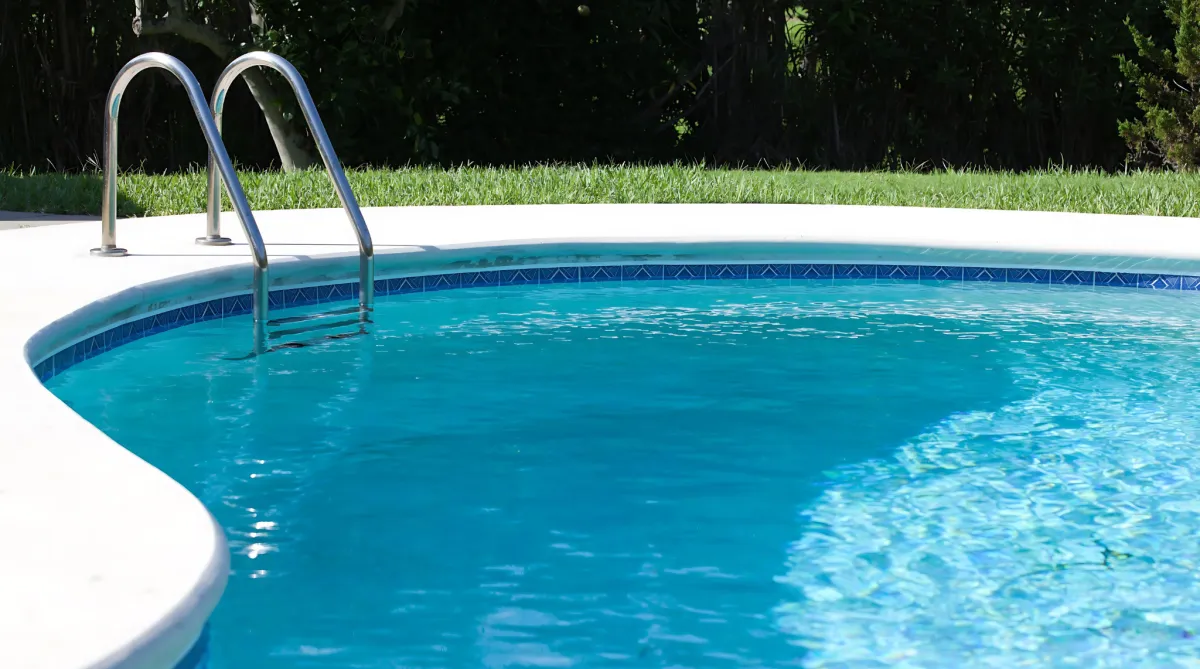 Clear blue swimming pool with metal ladder.