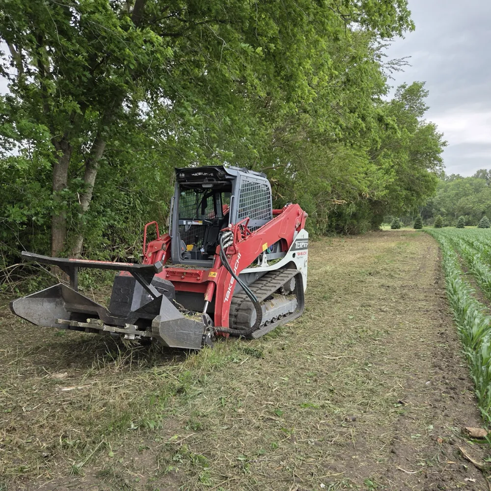 Heavy equipment clearing land. Excavators and a chipper or grinder process trees and brush. This is large scale land clearing.