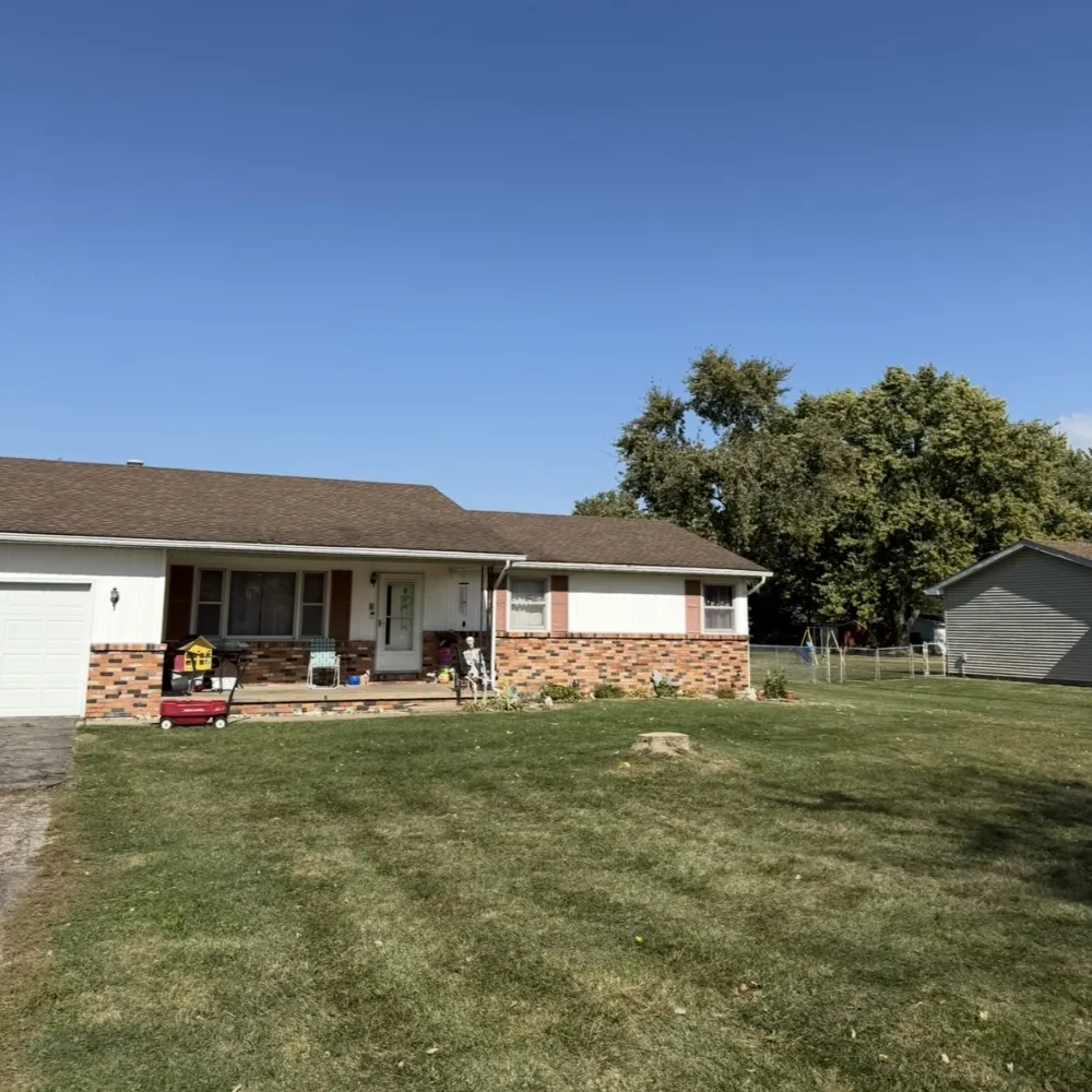 A worker in a lift basket guiding a large cut trunk section being lowered by crane or rigging. This is precision removal near buildings.