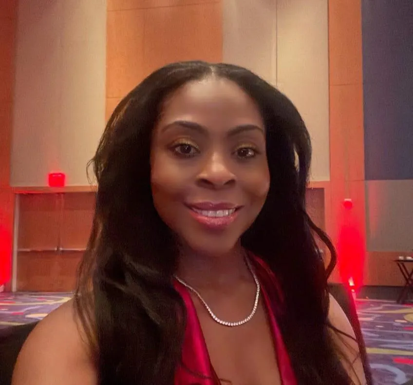 Confident Black woman in colorful casual attire reflecting on growth and success at an alumni gala celebration.