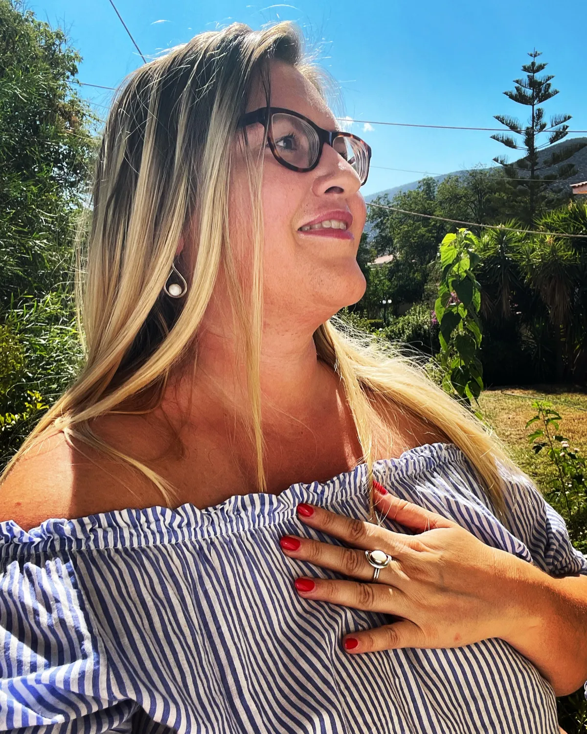 Eleni Iatridi with her hand on her heart, looking up in the sunlight