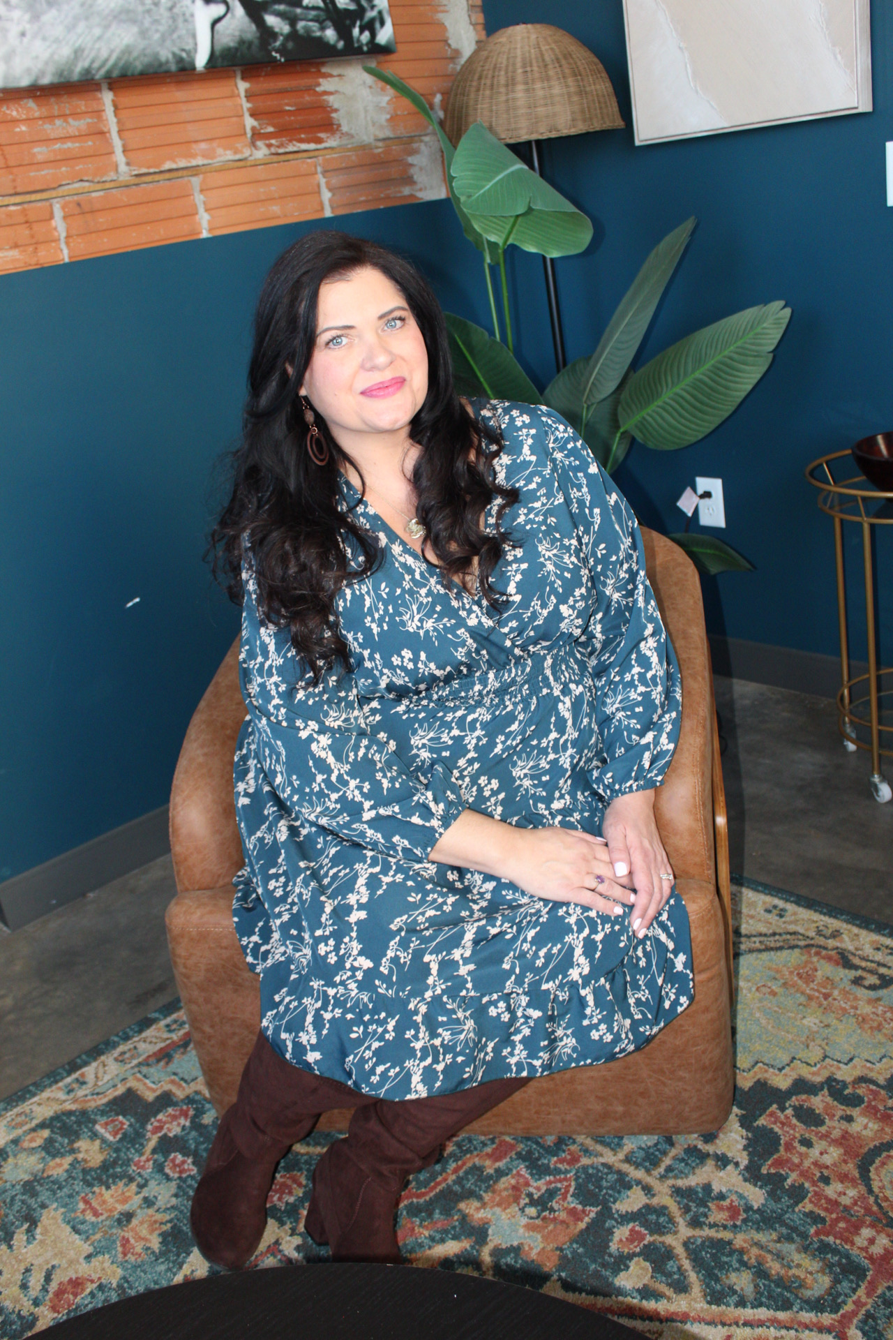 A woman holding a microphone standing in front of pink and silver balloons at an event