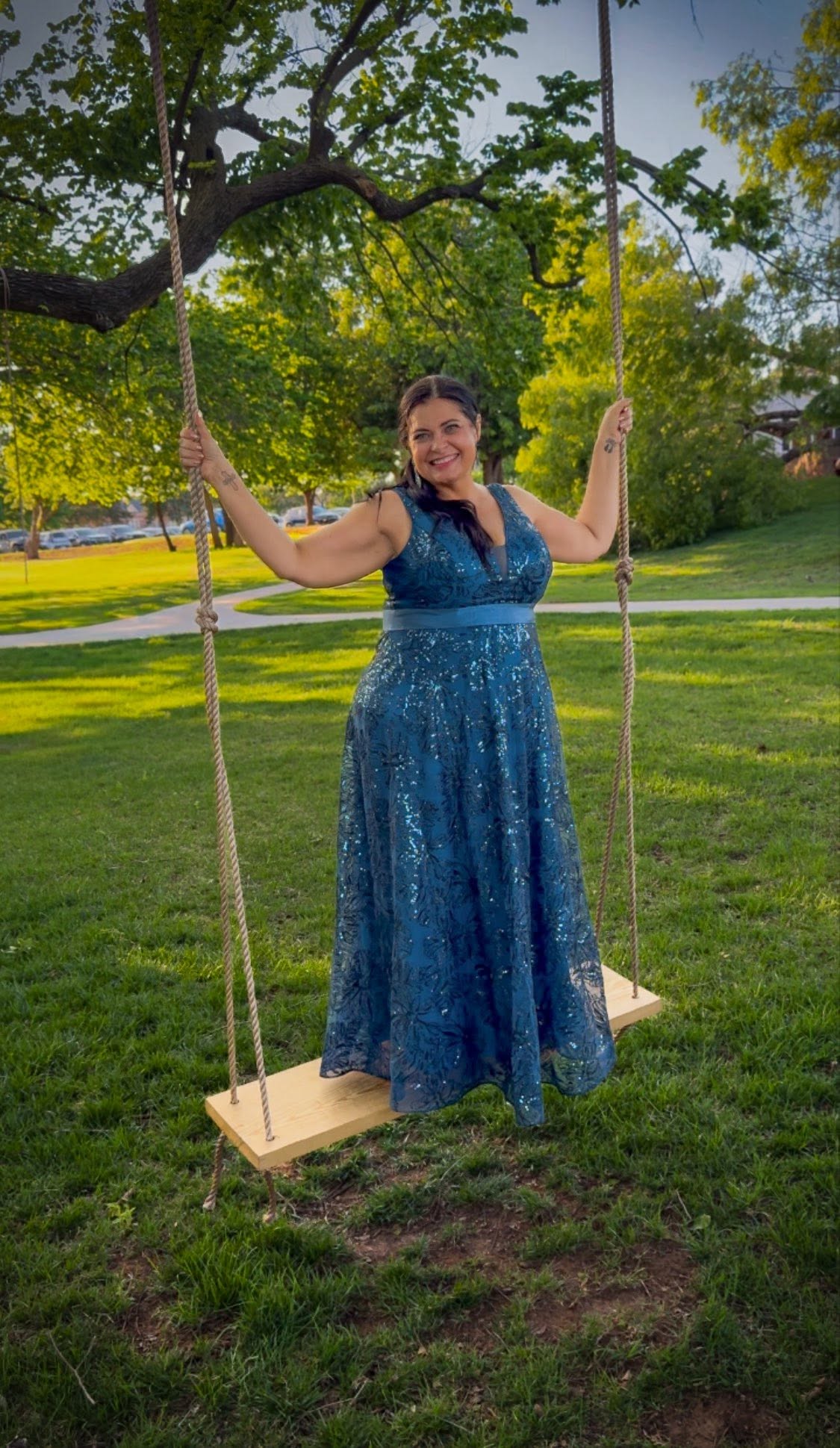 Blythe smiles at the camera while standing on a swing hanging from a tree.