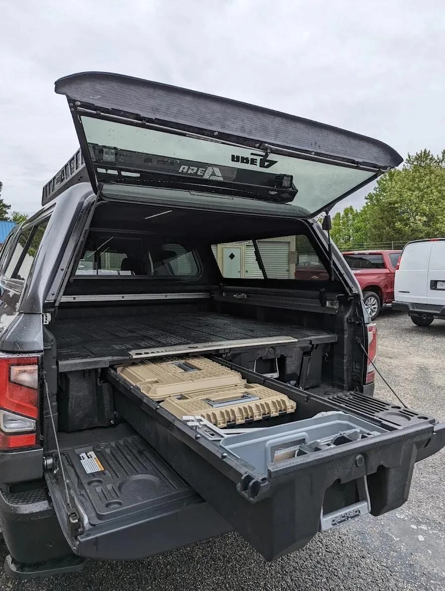 Midday workshop shoot of RidgeCraft Boltline cap mounted on a contractor pickup, crisp natural light, focus on hinge, gasket and cargo clearance, shallow depth of field to emphasize construction and finish — photorealistic functional view.