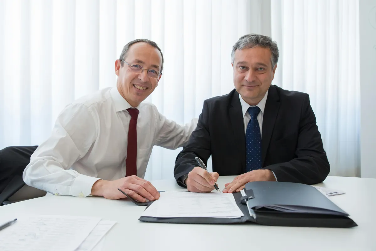 Two business partners shaking hands in an office after finalizing a buy/sell agreement