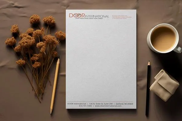 notepad laid flat on desk with coffee, pencils and flowers