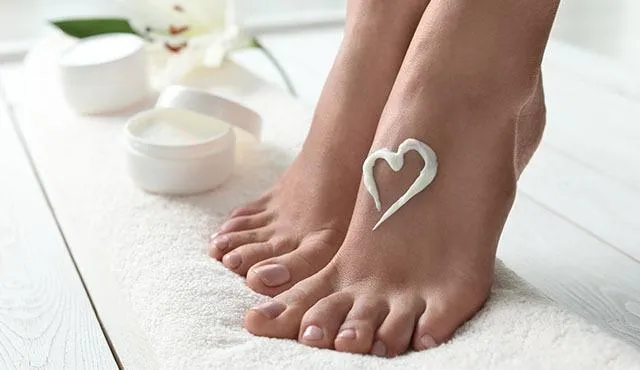 Image of women's feet with some lotion in the shape of a heart.  
