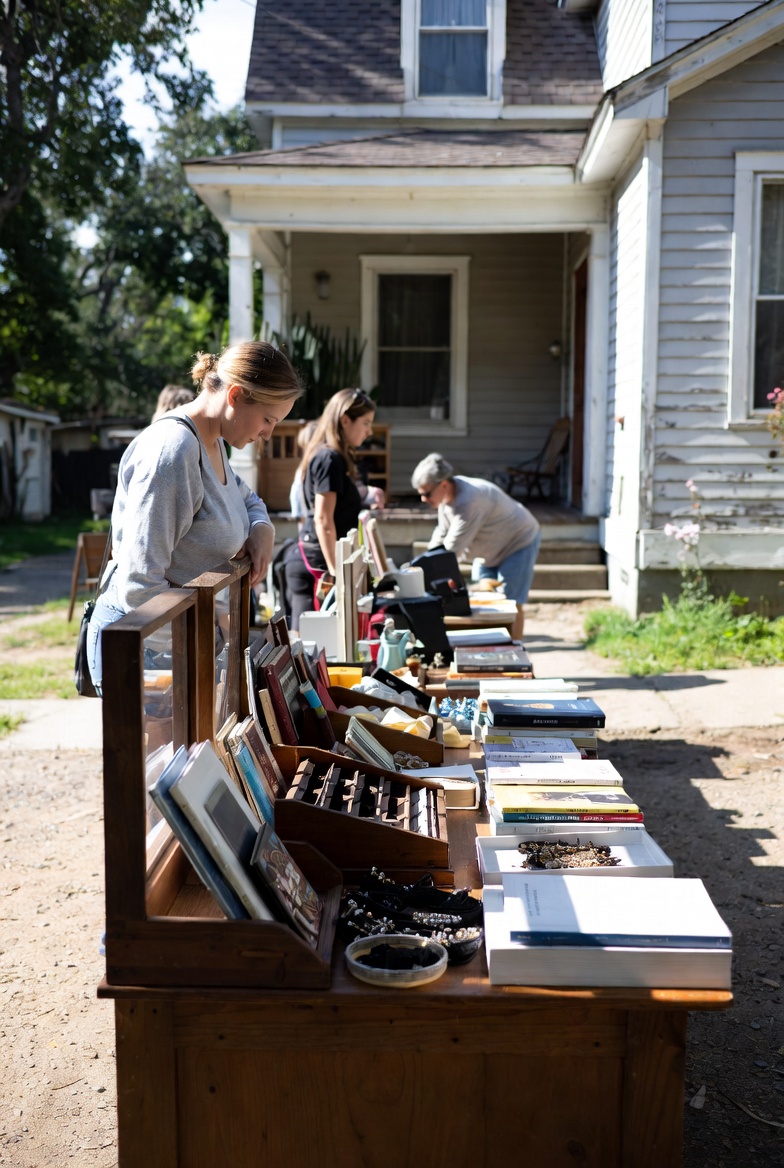 People browsing items displayed at an outdoor estate sale or organized decluttering event, representing senior support services.