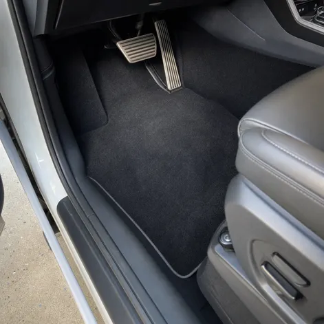 Professional automotive carpet replacement installed in a vehicle interior by EM Upholstery showing clean black carpet floor mat with aluminum pedals