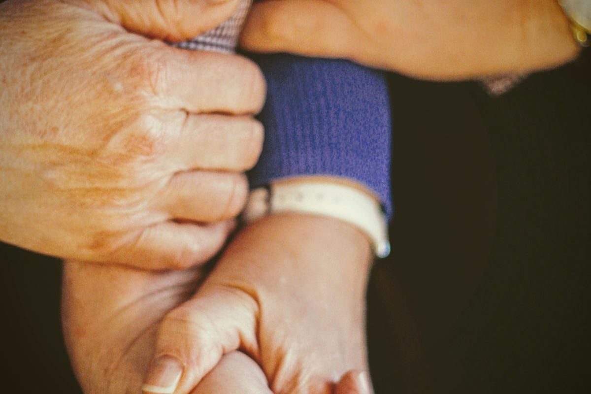 Family member holding an older parent's hands, supporting a loved one with memory loss in Elgin, IL