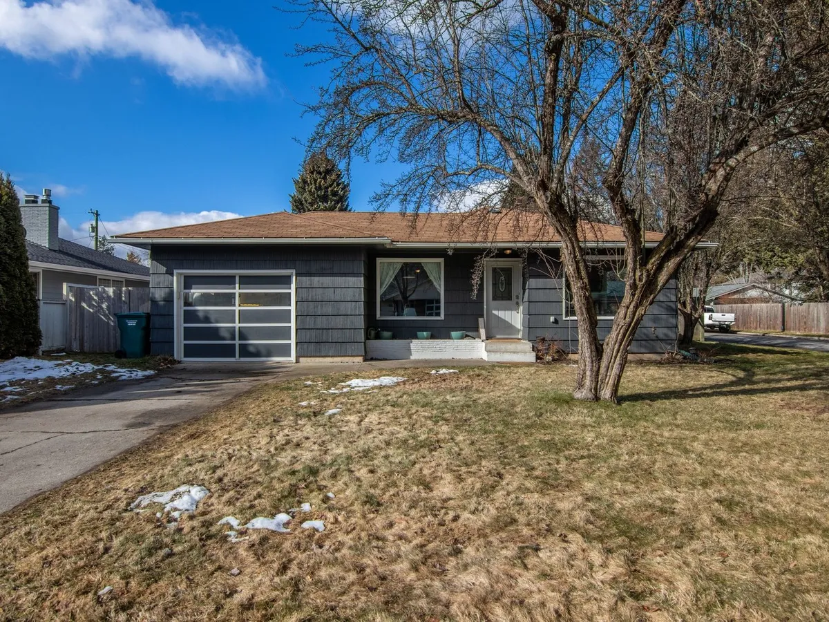 Single-story ranch house with a one-car garage and a bare tree in the front yard in late winter
