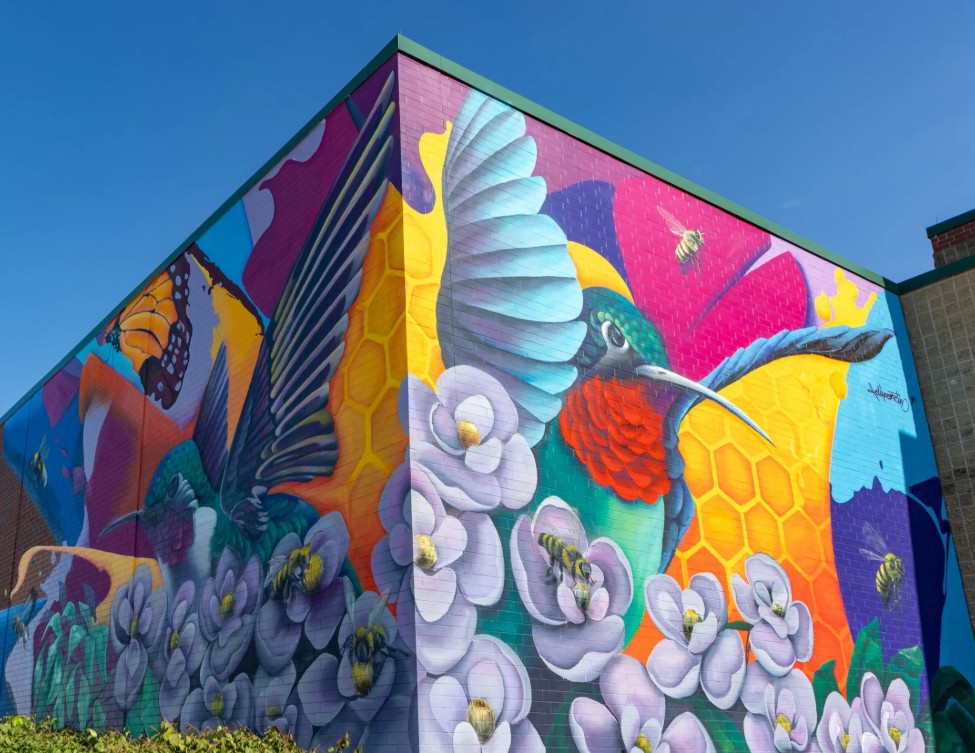 Large outdoor mural featuring a hummingbird and flowers in Lowell, Arkansas