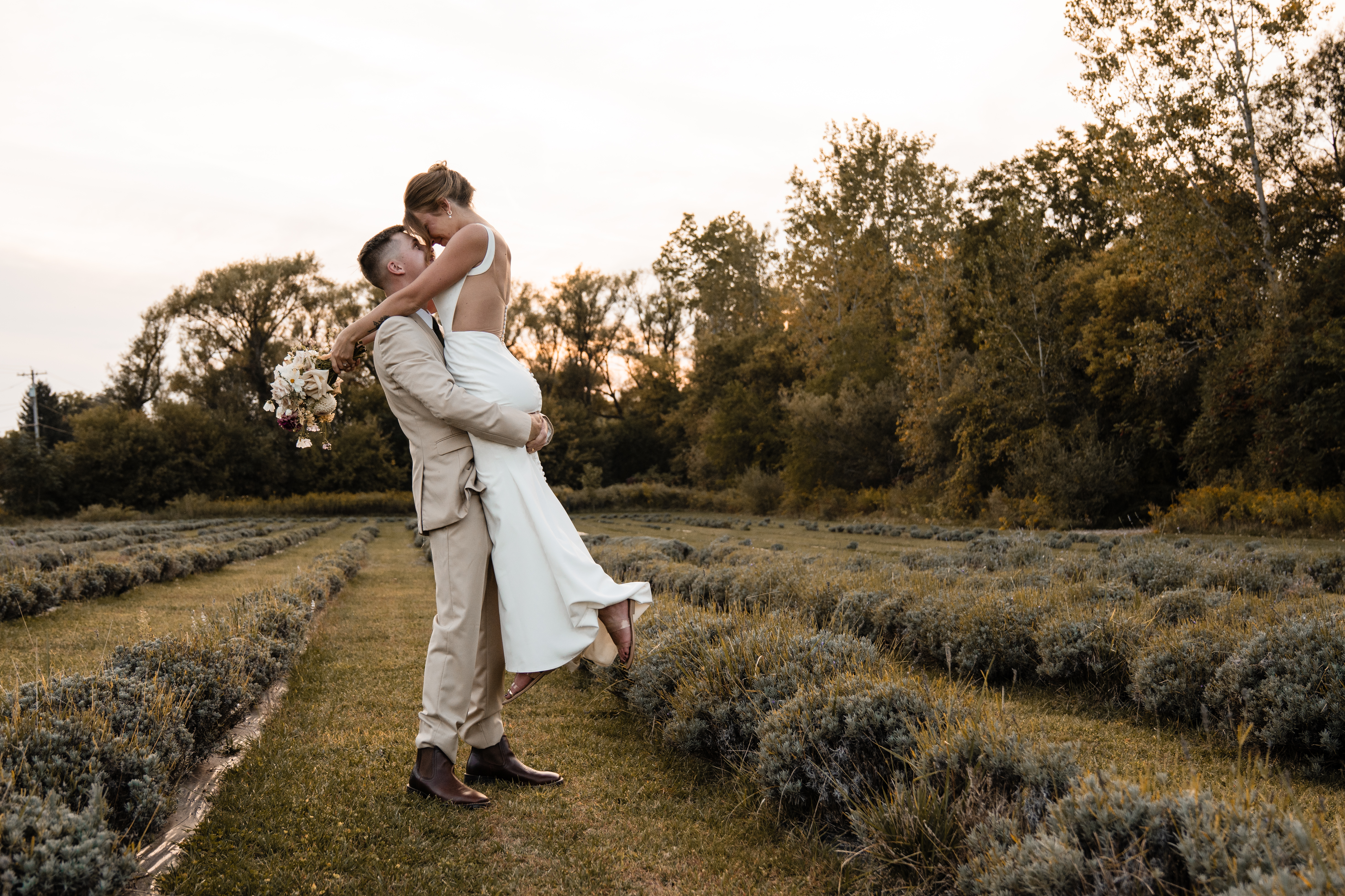 Bride in a white dress holding a bouquet outdoors.