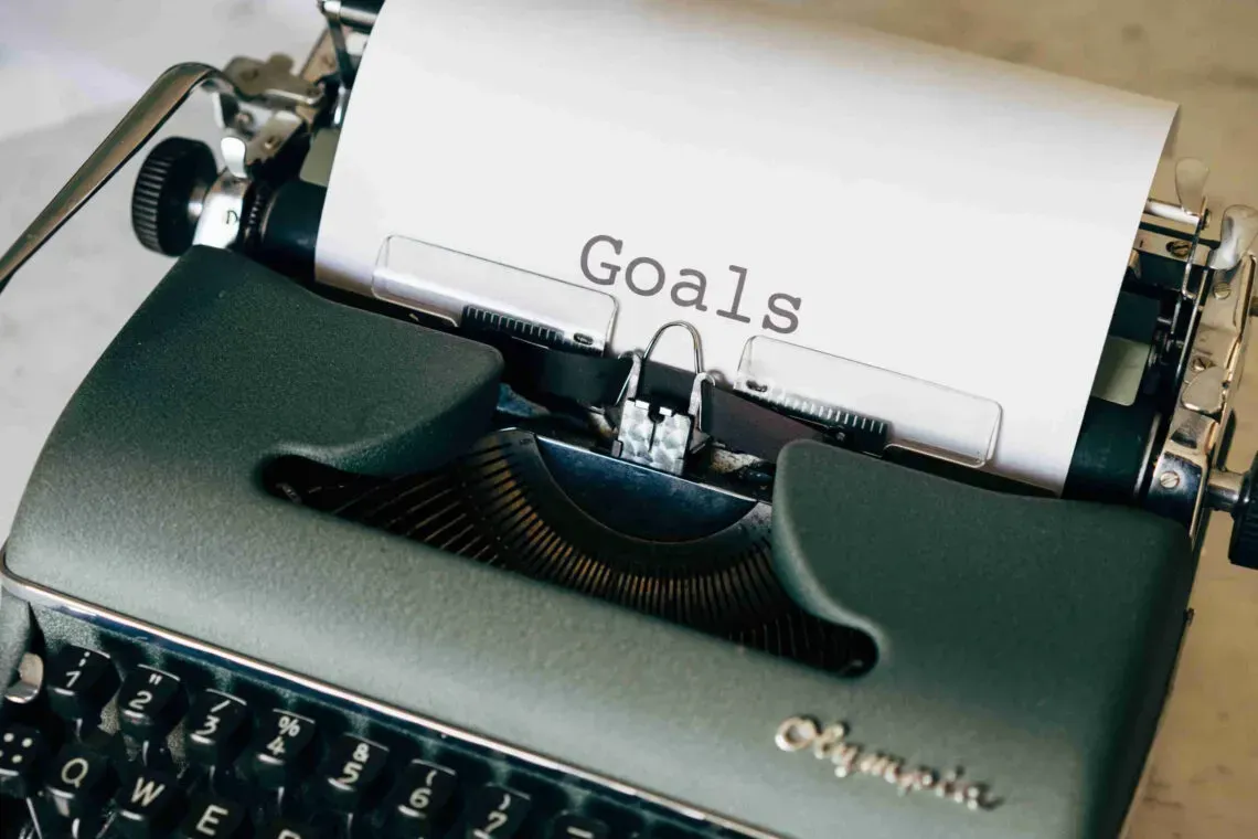 An old-fashioned typewriter with the word 'Goals' typed on a piece of paper, symbolizing the concept of goal setting and planning.