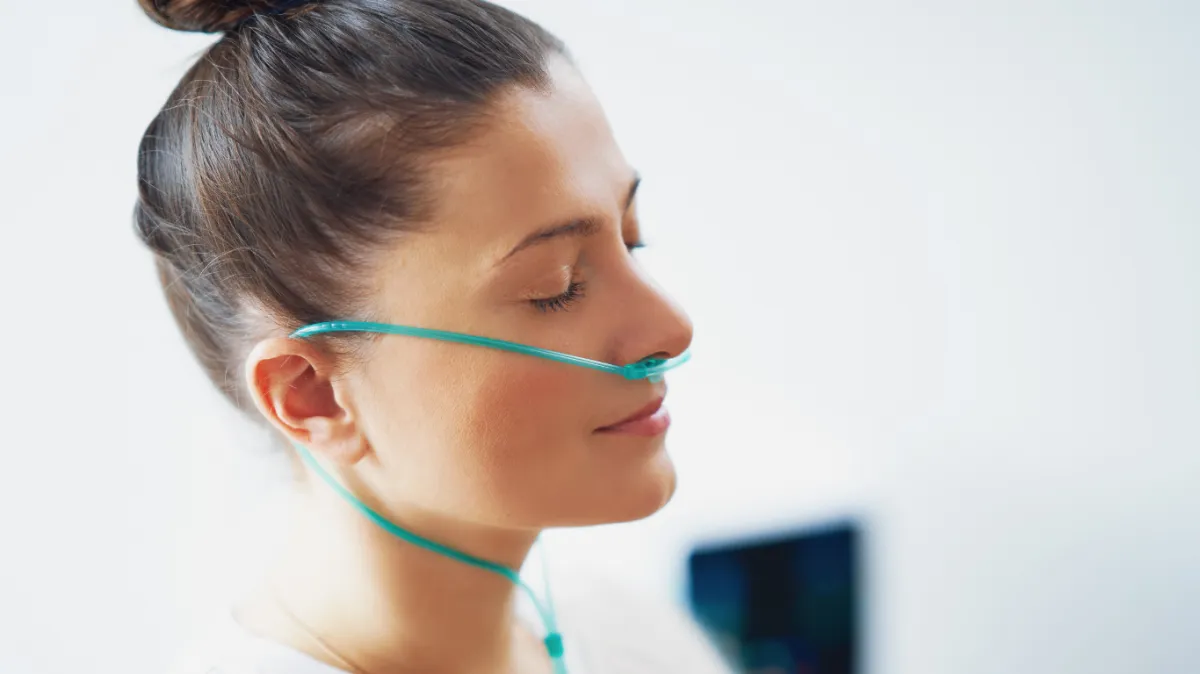 woman wearing black top top holding black dumbbells standing in front of mirror