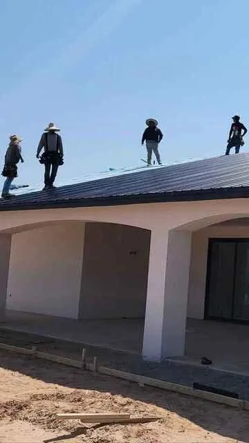 Roofers discussing project on top of a black metal roof.