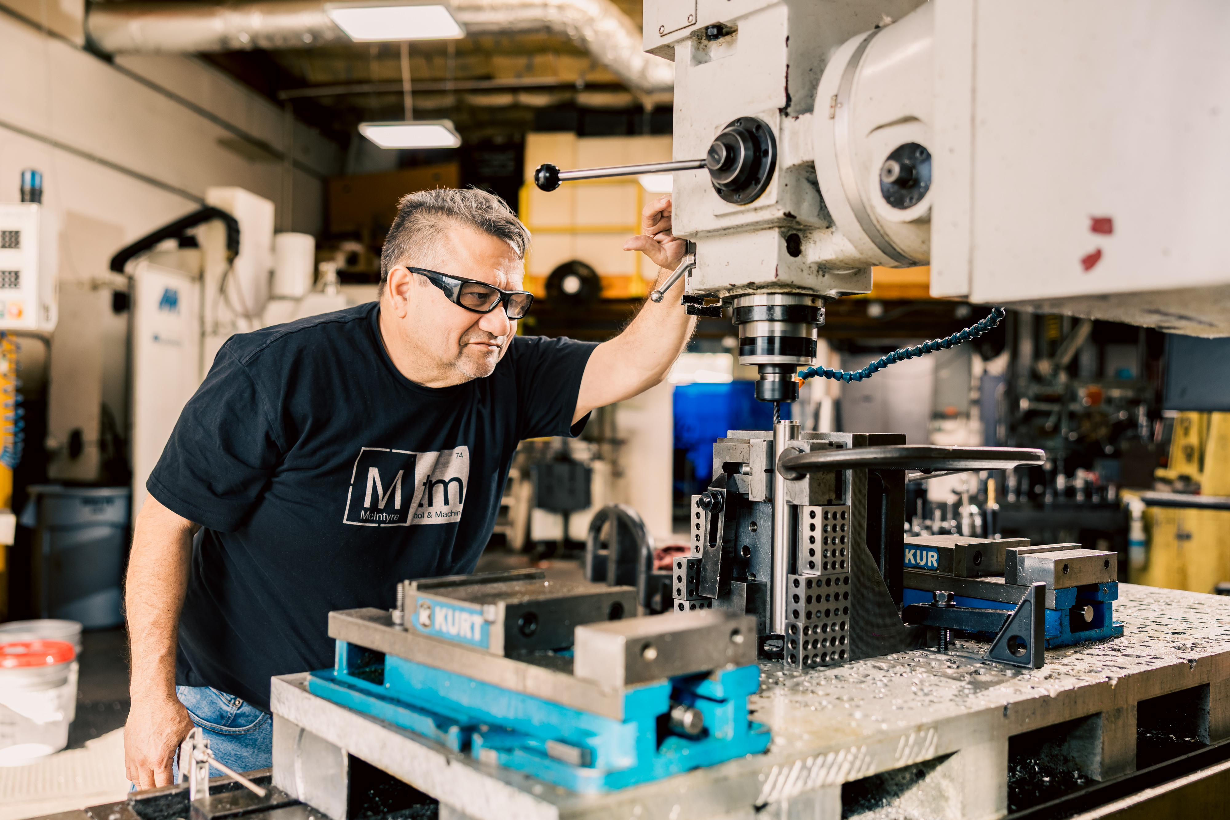 Lalo, an experienced machinist, is programming and setting up a CNC vertical mill for custom tooling in a workshop.