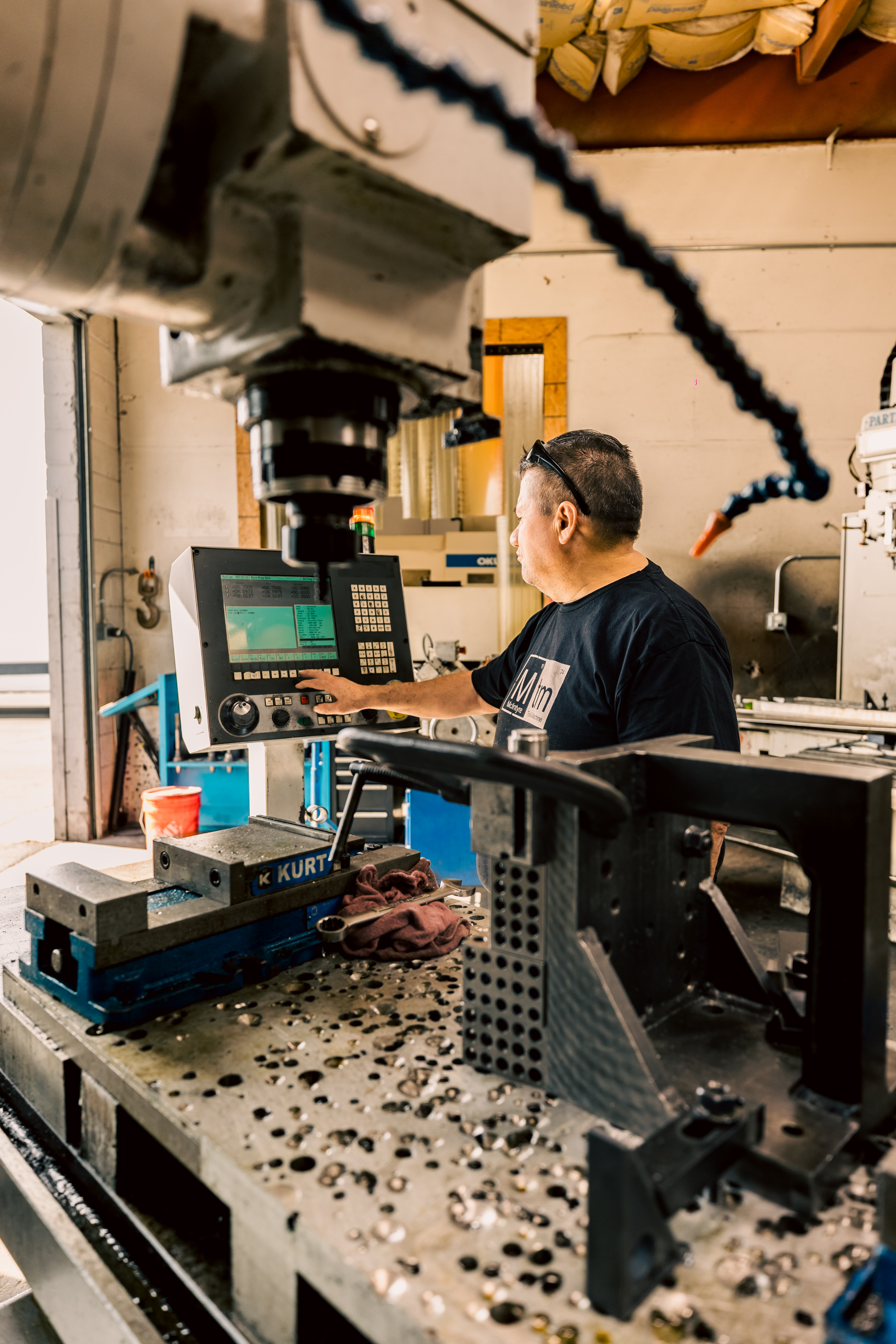 A machinist programming and setting up a Milltronics MB30 vertical mill for custom tooling in the workshop.