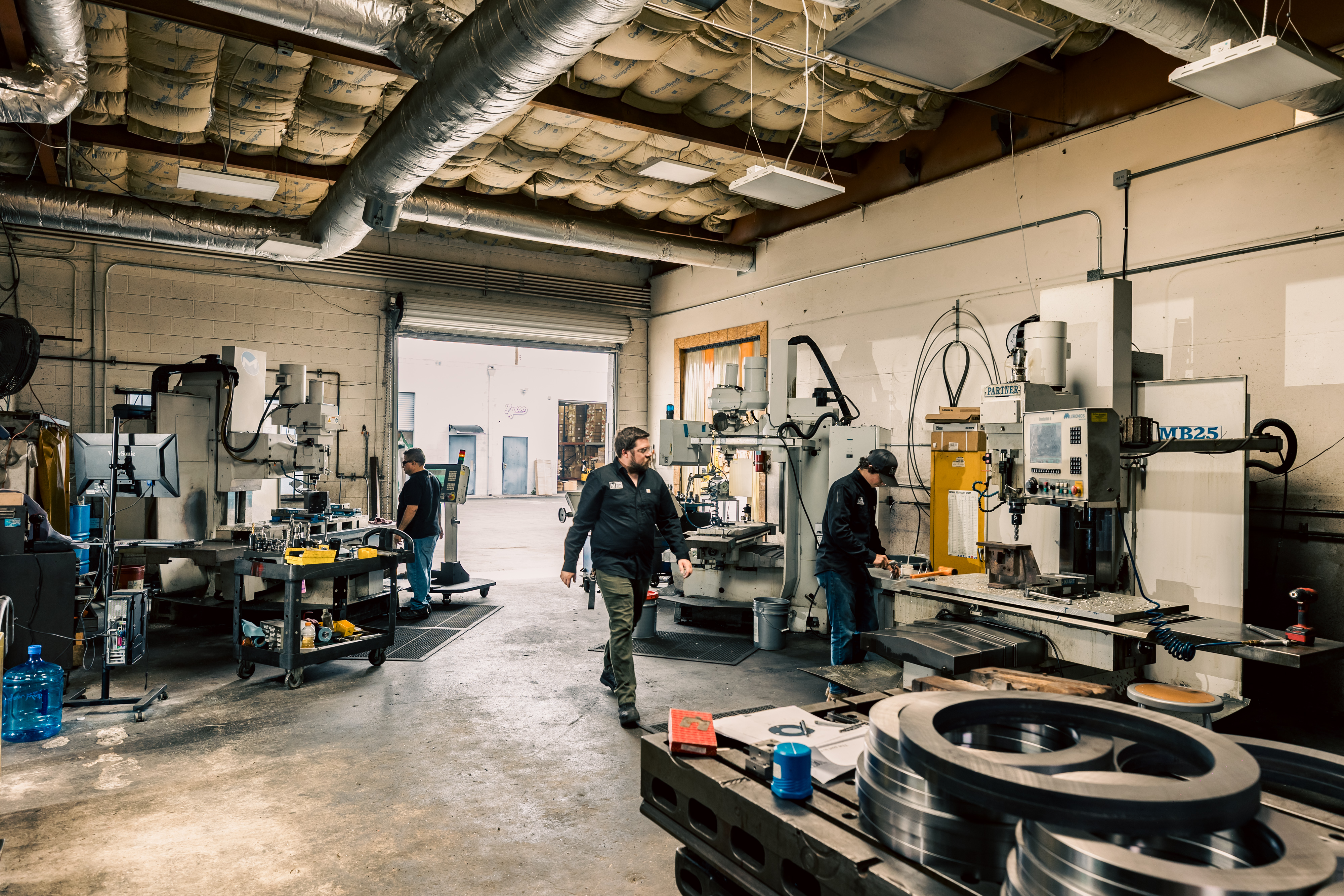 A fabricator welding on a perforated metal table, sparks and smoke in the workshop.