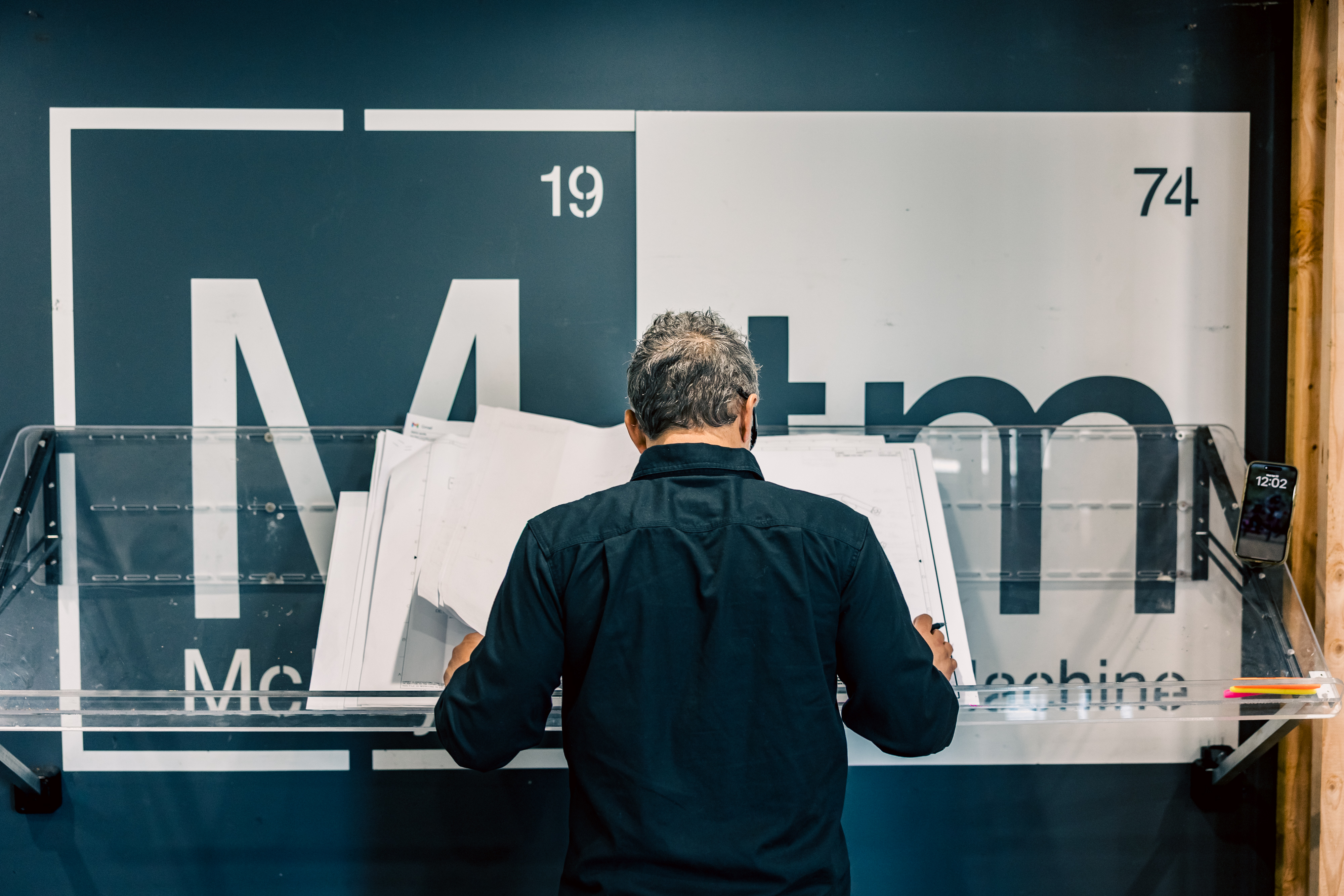 Dustin McIntyre reviewing engineering drawings at a drafting table in the MTM headquarters.