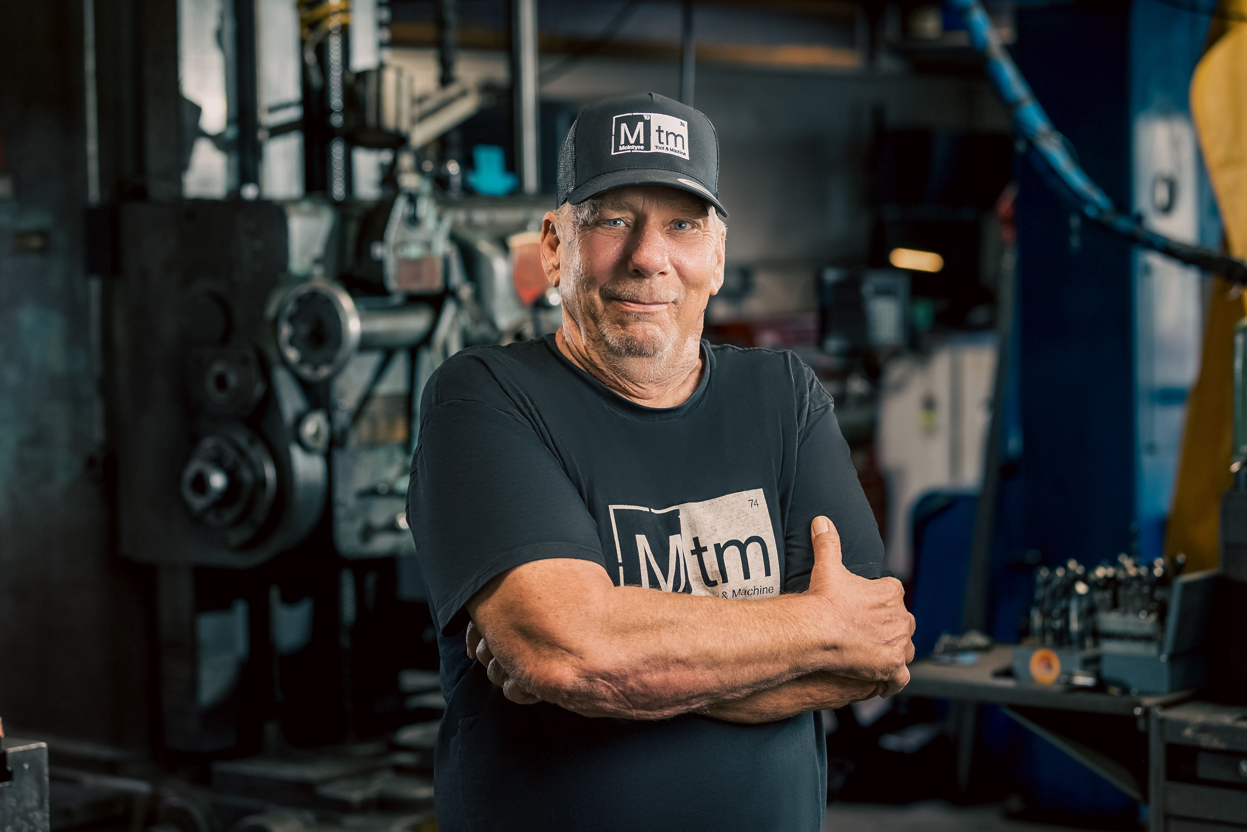 A professional portrait of Steve, Logistics Manager at MTM, smiling with arms crossed wearing an MTM cap.