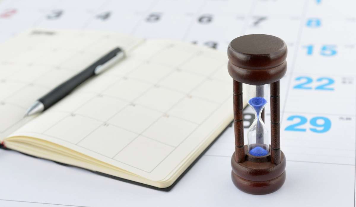 A close-up of two hands, one older and one younger, gently clasped over a table with soft natural light, symbolizing intergenerational support and community care. The background is softly blurred in warm neutral tones.