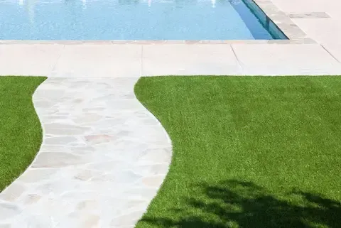 Artificial turf installation around pool and walkway by Desert Bloom Landscaping in Sunrise Manor