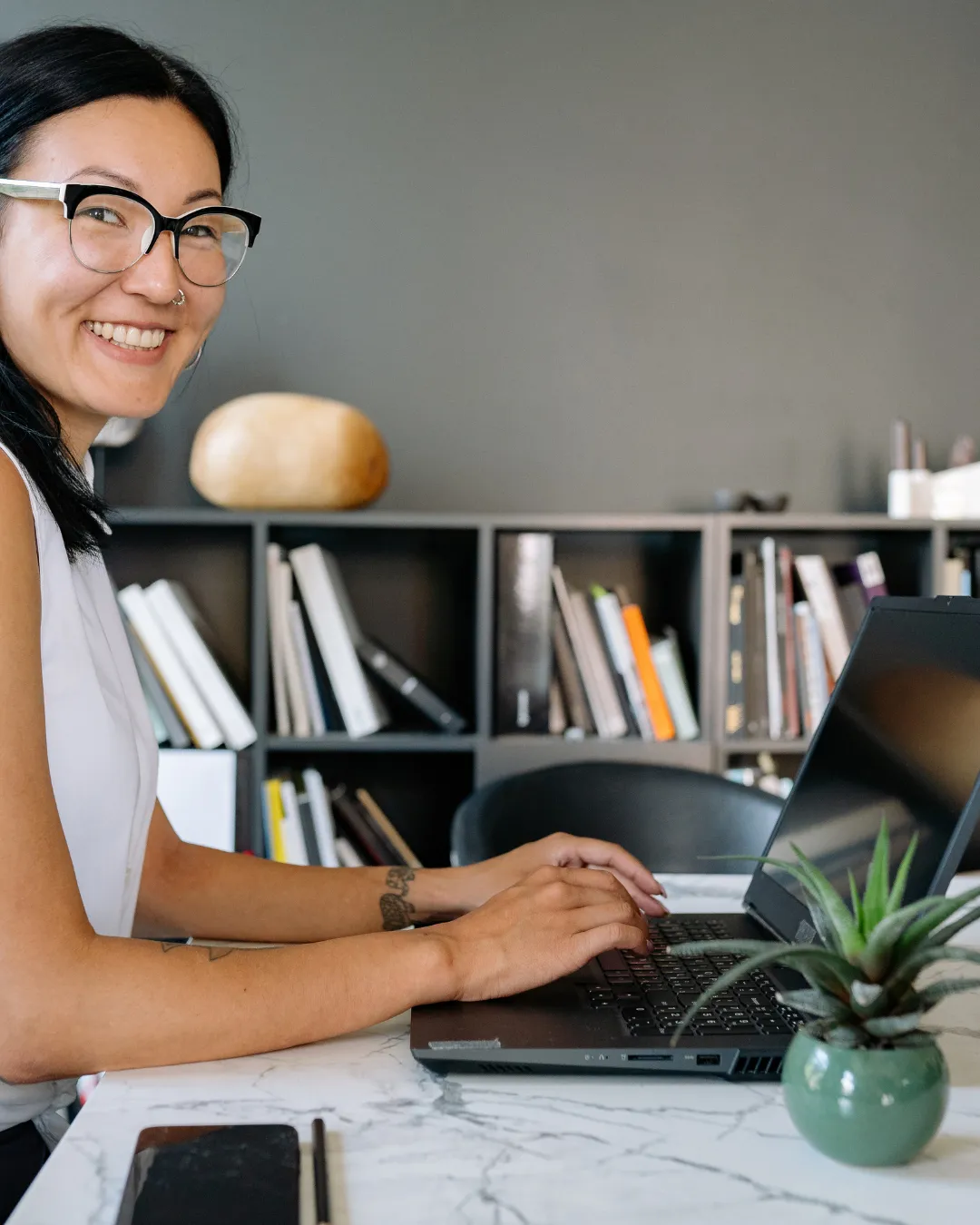Woman meditating at a desk with laptop.