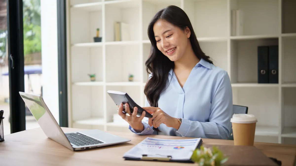 two women sitting on a bed using laptops