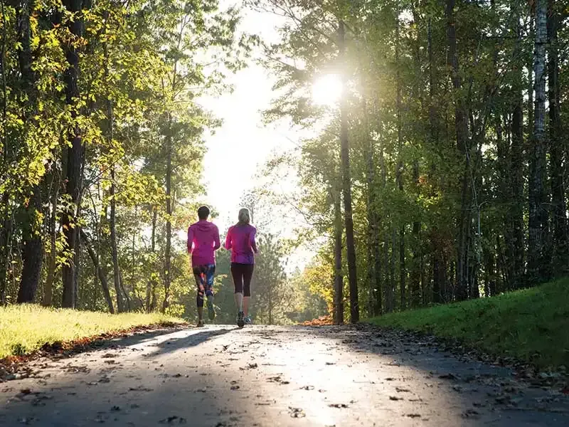 Couple running wooded trail Garner NC outdoor lifestyle Lake Benson Park