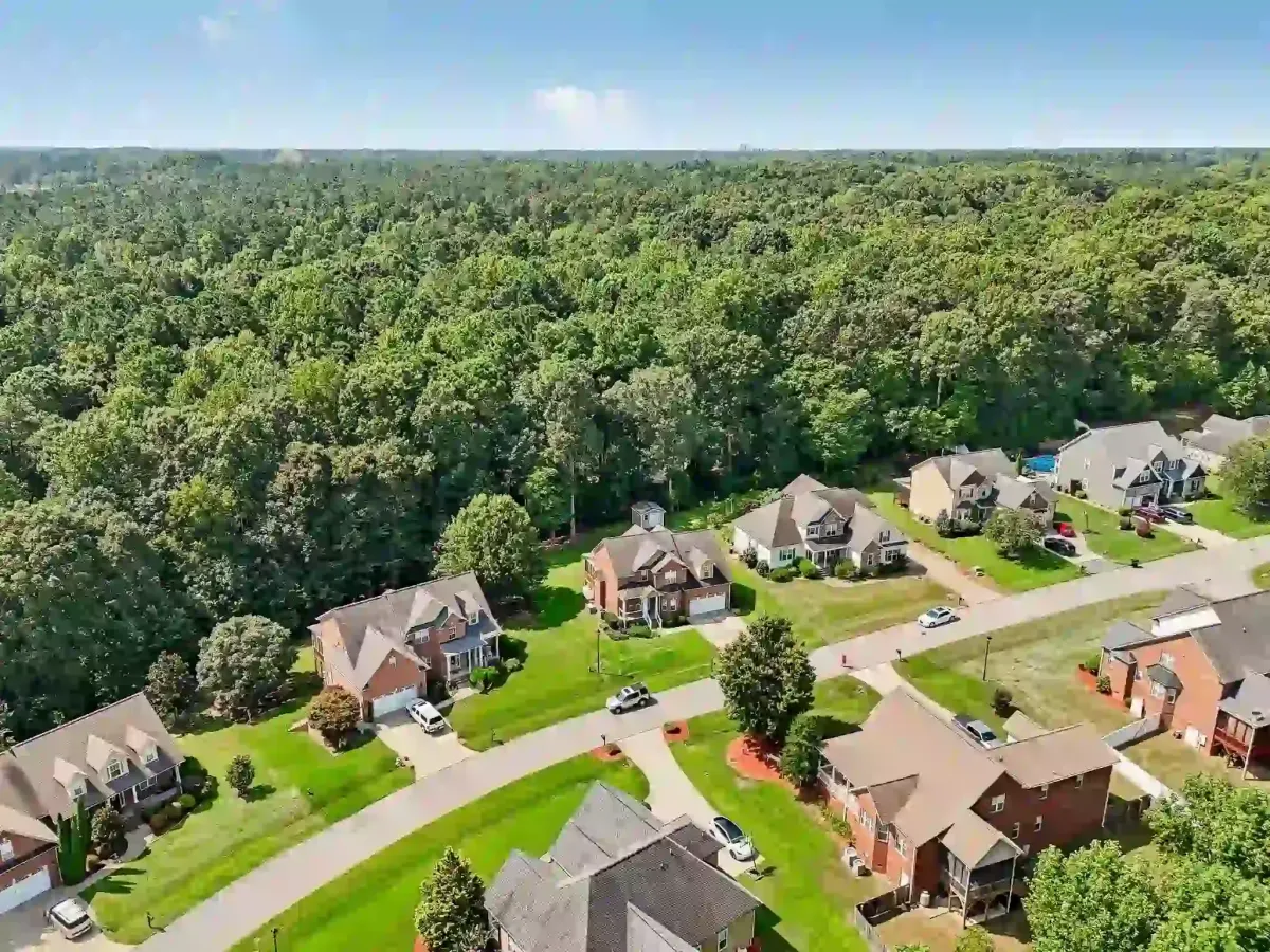 Aerial drone view of established Clayton NC neighborhood showing brick homes large lots and mature tree canopy Johnston County