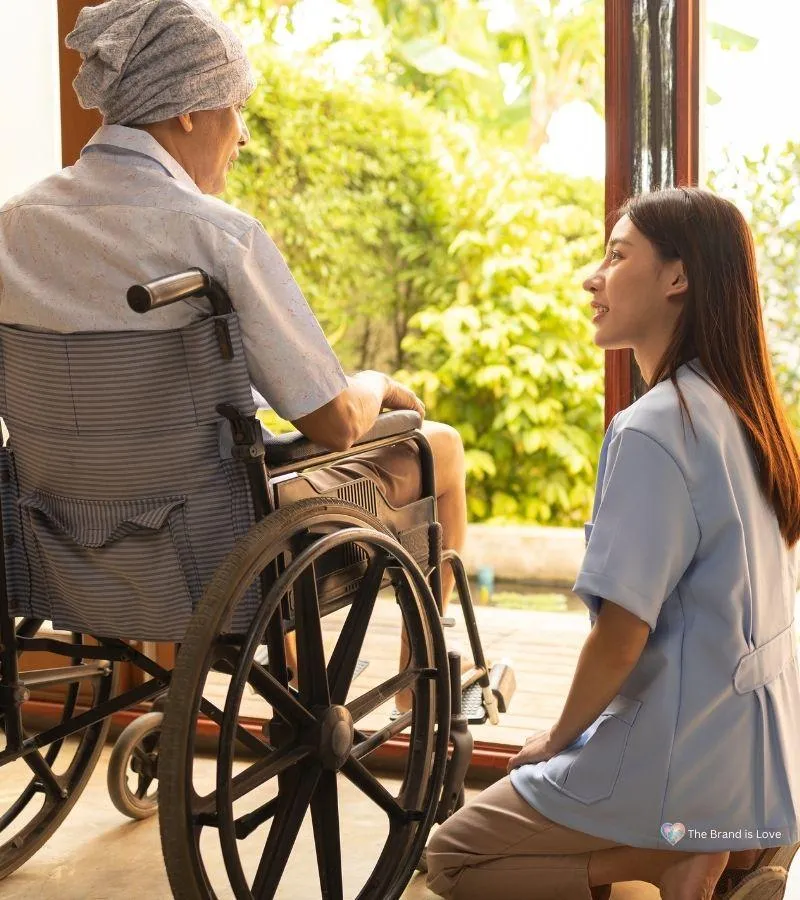 Facility employee kneeling and listening to an elderly person, signifying commitment to understanding your loved one’s preferences.