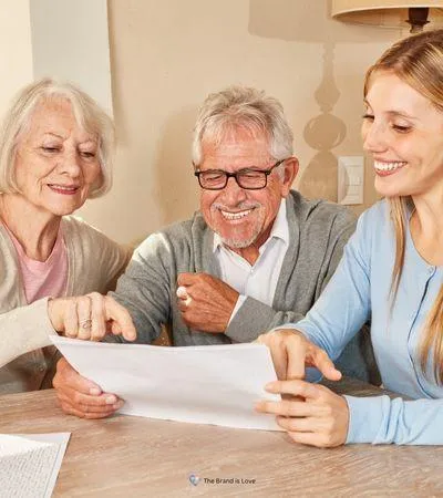 Image of an elderly couple and a woman reviewing legacy keepsakes, showcasing The Brand Is Love's legacy planning and documentation services.