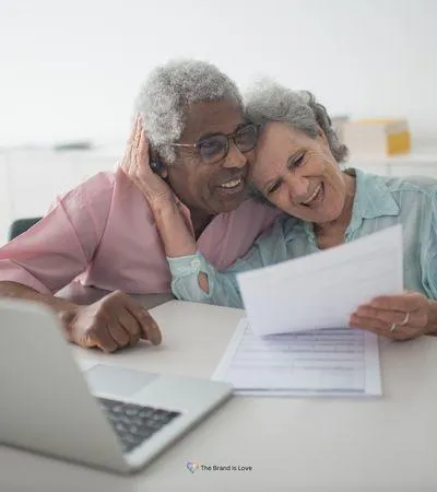 Elder couple smiling as they sit in front of a computer and review papers, showing the joy of preserving their legacy.