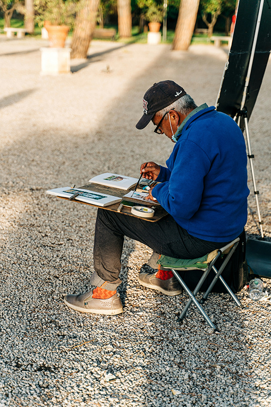 Man painting on a small chair.