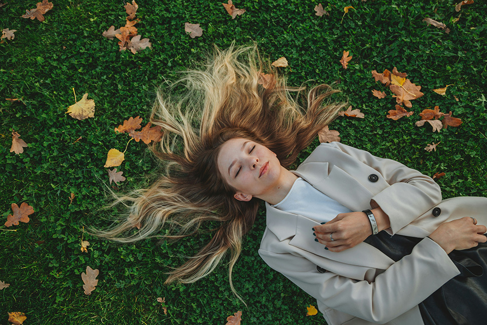 Woman with long hair laying on the grass.